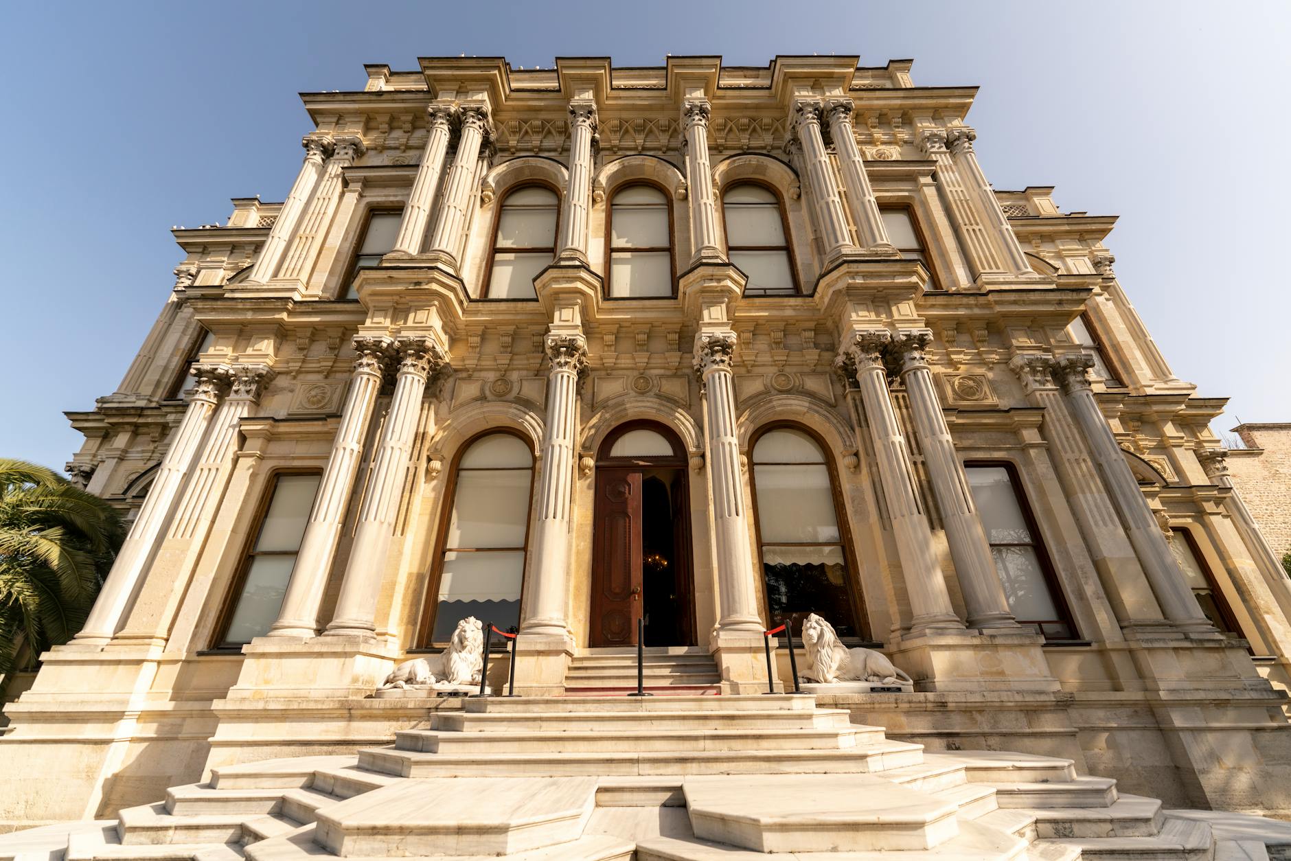 Die prachtvolle Eingangsfassade des Beylerbeyi-Palastes mit weißen Löwenstatuen vor der Treppe.