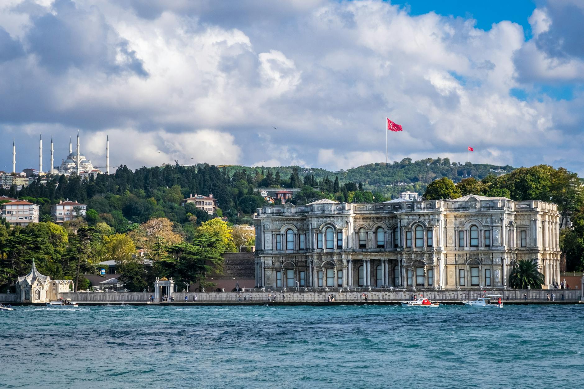 Frontalansicht des Küçüksu-Kasrı mit wehenden türkischen Flaggen unter blauem Himmel.