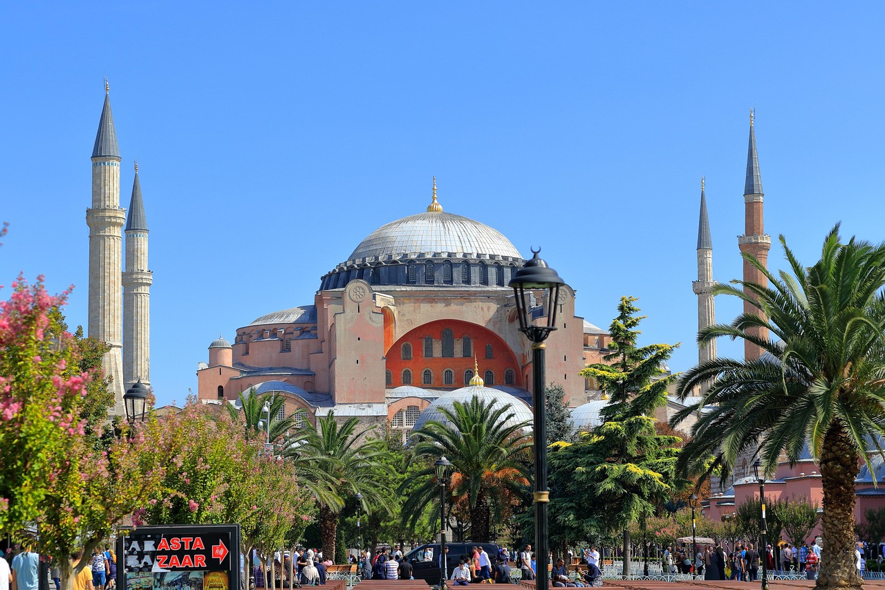 Die beeindruckende Hagia Sophia in Istanbul eingerahmt von grünen Palmen und Blumen.
