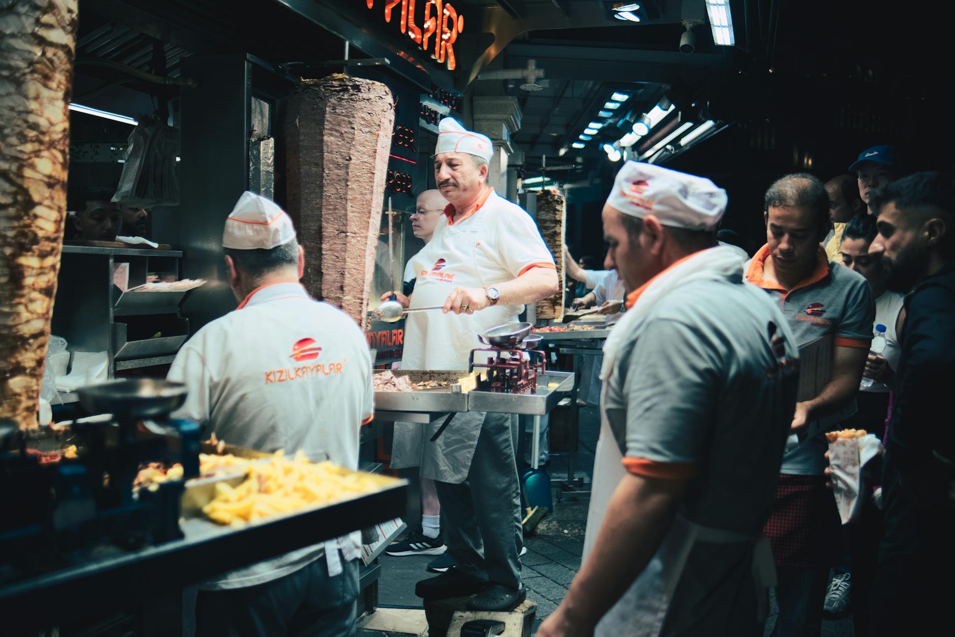 Ein erfahrener Koch schneidet hauchdünne Scheiben vom Fleischspieß für einen Iskender Kebab ab.