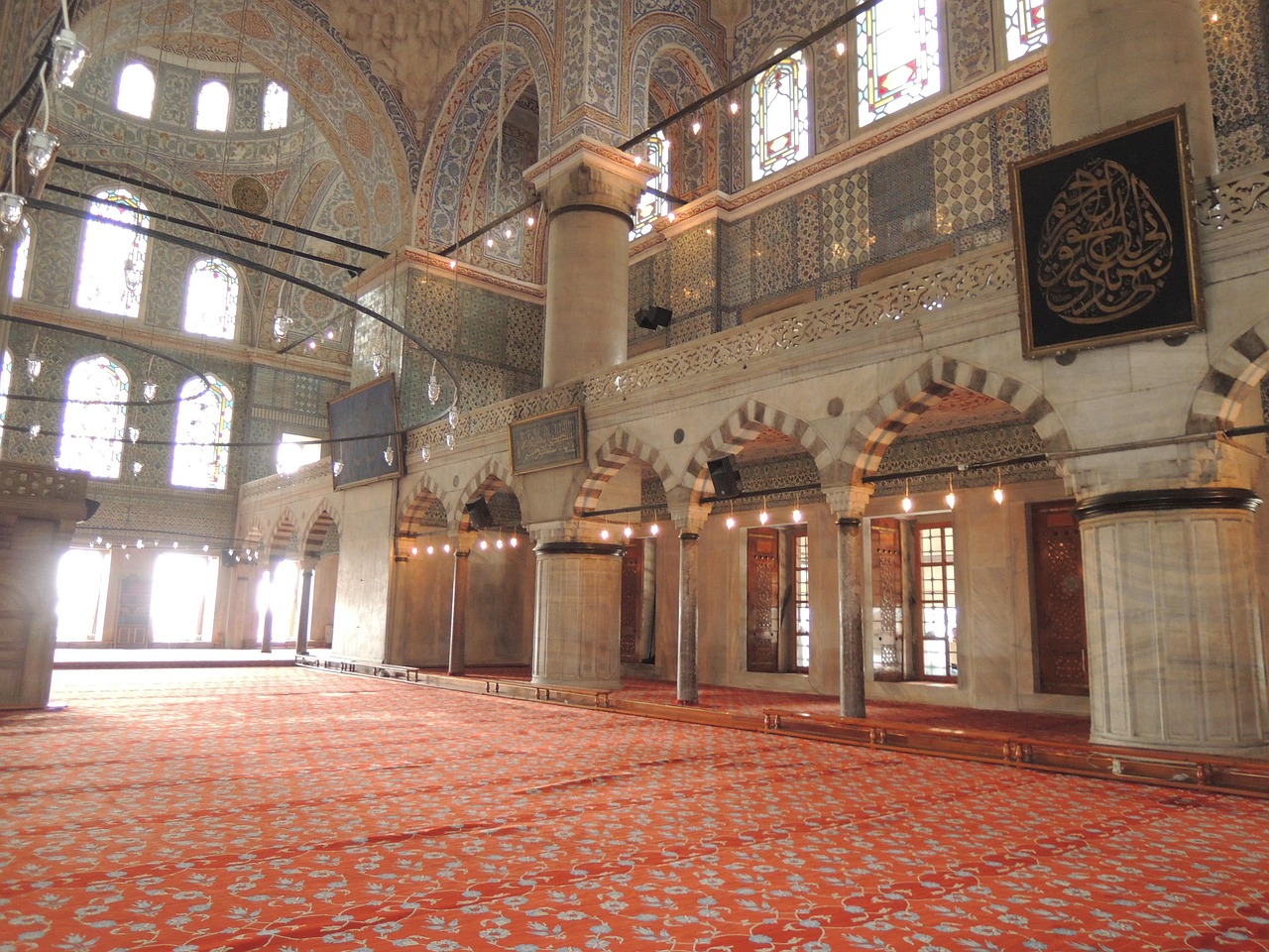 Der Innenraum einer Istanbuler Moschee mit kunstvollen Teppichen und verzierten Wänden.