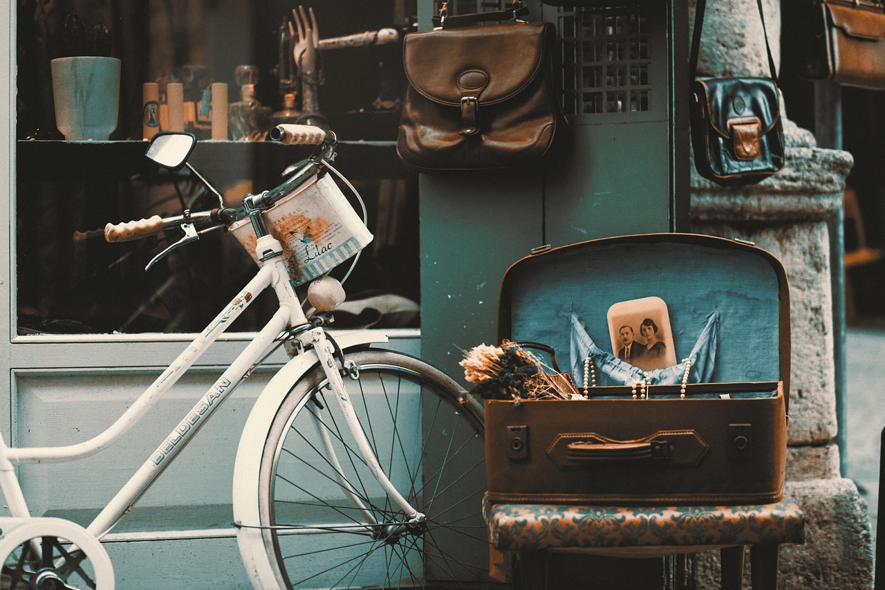 Ein weißes Fahrrad vor einem schicken Vintage-Laden mit Lederhandtaschen und Koffern.