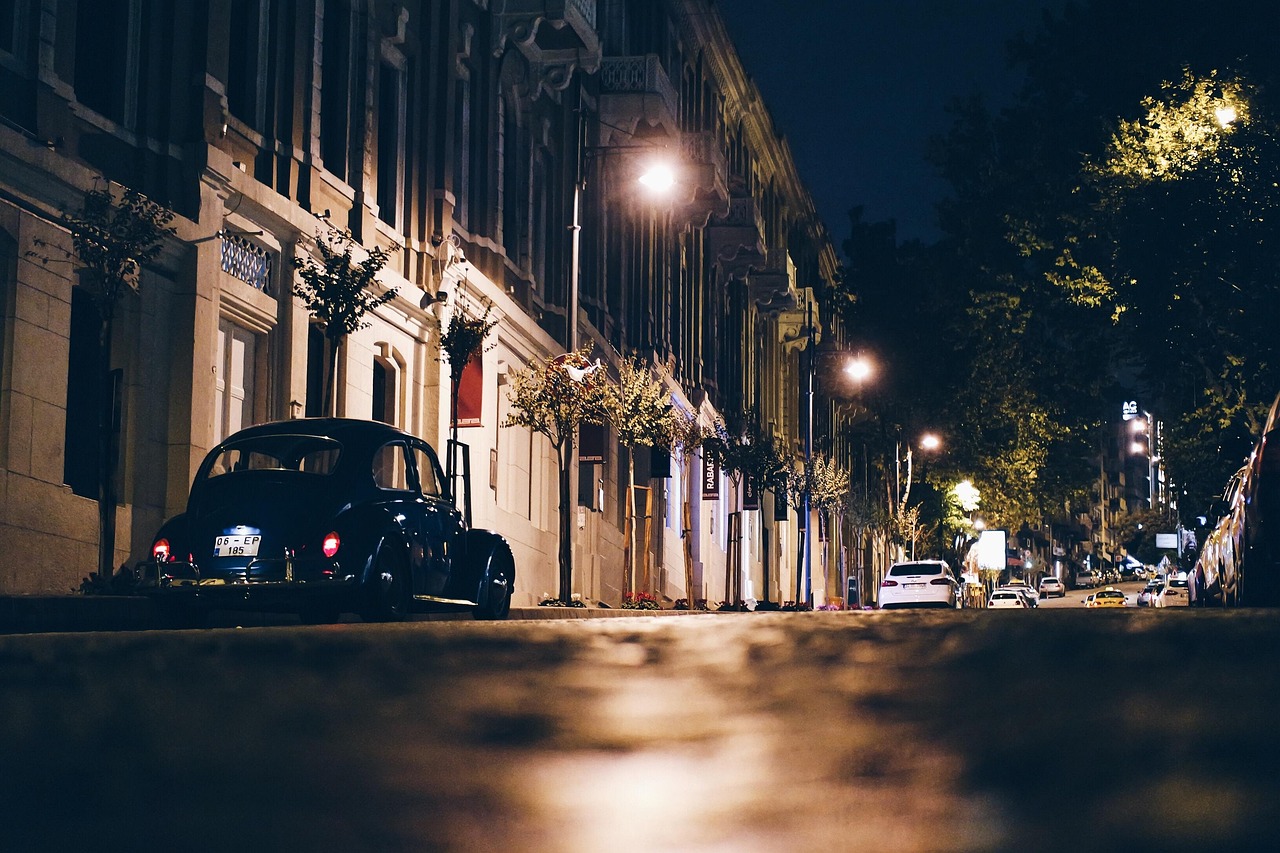 Eine beleuchtete Straße in Nişantaşı mit einem parkenden Oldtimer bei Nacht.