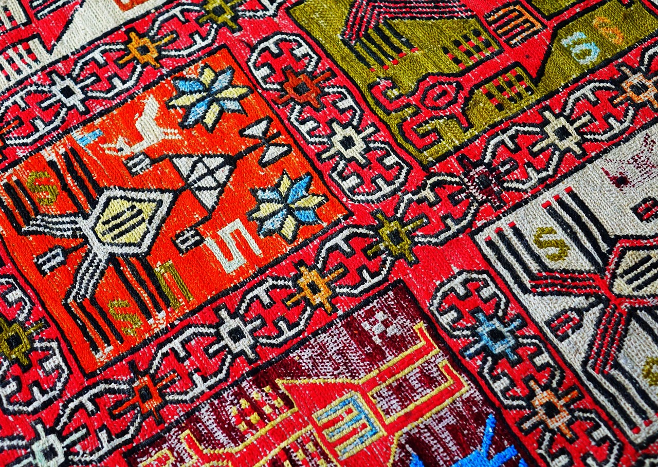 Nahaufnahme eines traditionellen, farbenprächtigen Anatolischen Teppichs mit komplexen geometrischen Mustern und leuchtend roten Akzenten, wie er typischerweise auf den Basaren in Istanbul beim "Feilschen wie ein Local: Mein Guide für entspanntes Shoppen auf Istanbuls Basaren" angeboten wird. Die Detailansicht betont die Textur und die Handwerkskunst des Produkts, das ein zentrales Element des Einkaufserlebnisses darstellt.