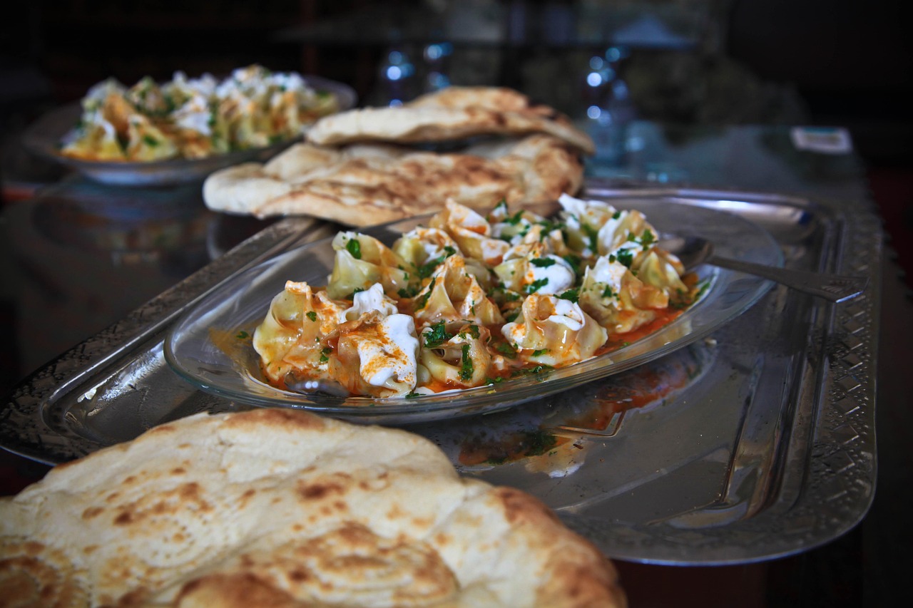 Traditionelle türkische Mantı serviert mit cremigem Joghurt und würziger Sauce auf Glasgeschirr.