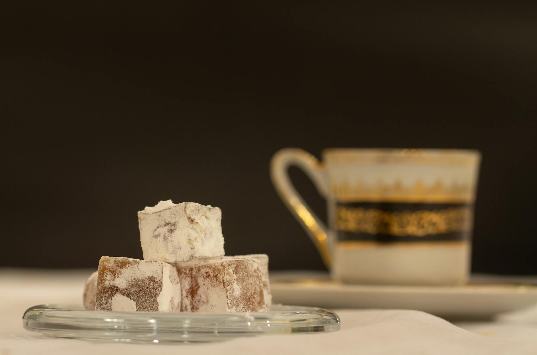 Nahaufnahme von türkischem Honig (Lokum) bestäubt mit Puderzucker, serviert mit einer verzierten Tasse türkischen Kaffees, typisch für die türkische Gastfreundschaft in Istanbul.