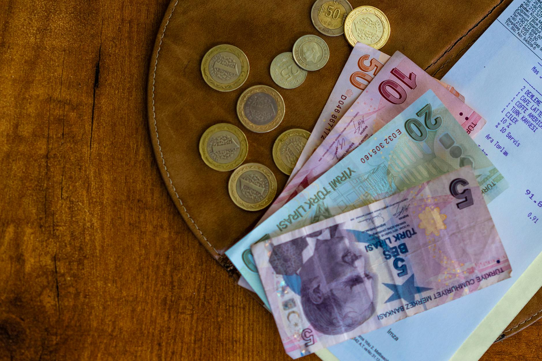 Türkische Lira Geldscheine und Münzen liegen neben einer Quittung auf dem Tisch.